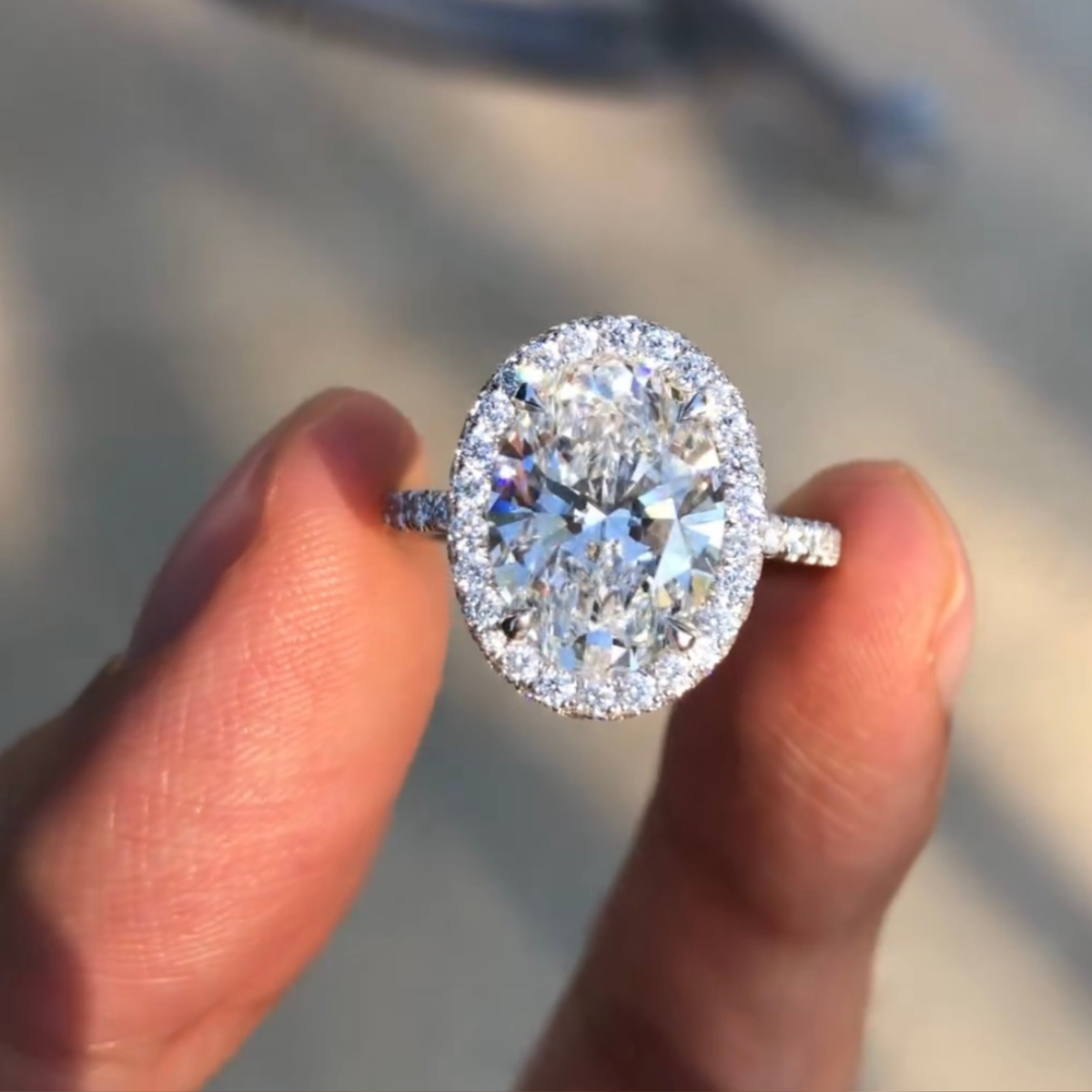 Diamond ring held between fingers with a blurred background