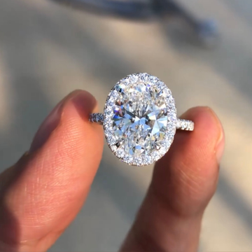 Diamond ring held between fingers with a blurred background